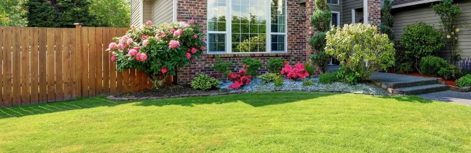 green grass with a flower bed in front of a house